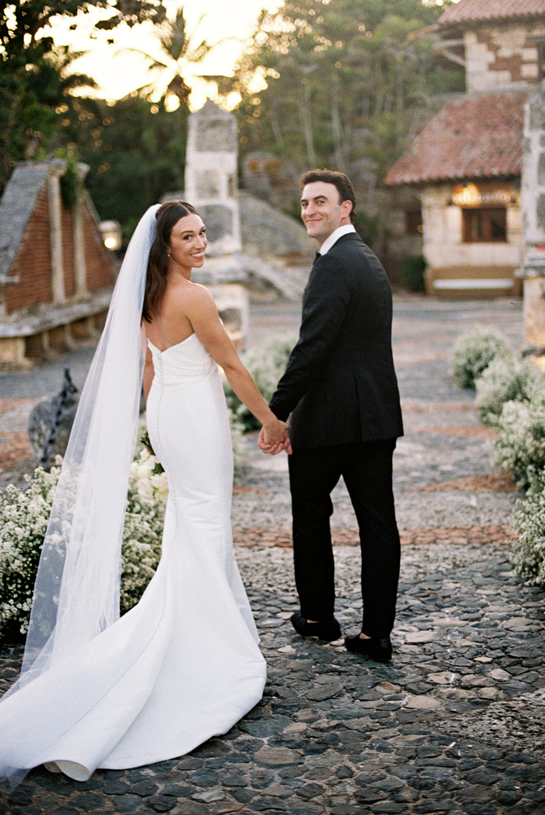 Bride and groom holding hands on the cobblestone streets of Altos de Chavón, Casa de Campo