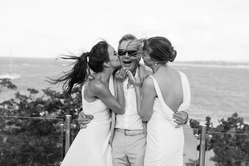 Two women in white kiss an older man on the cheeks during cocktail hour at Casa Colonial, Puerto Plata