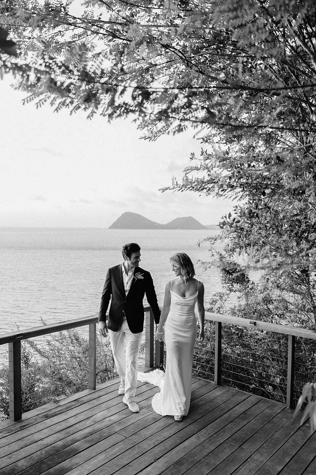 Elizabeth and Aaron walking hand in hand on the beach at sunset, black and white